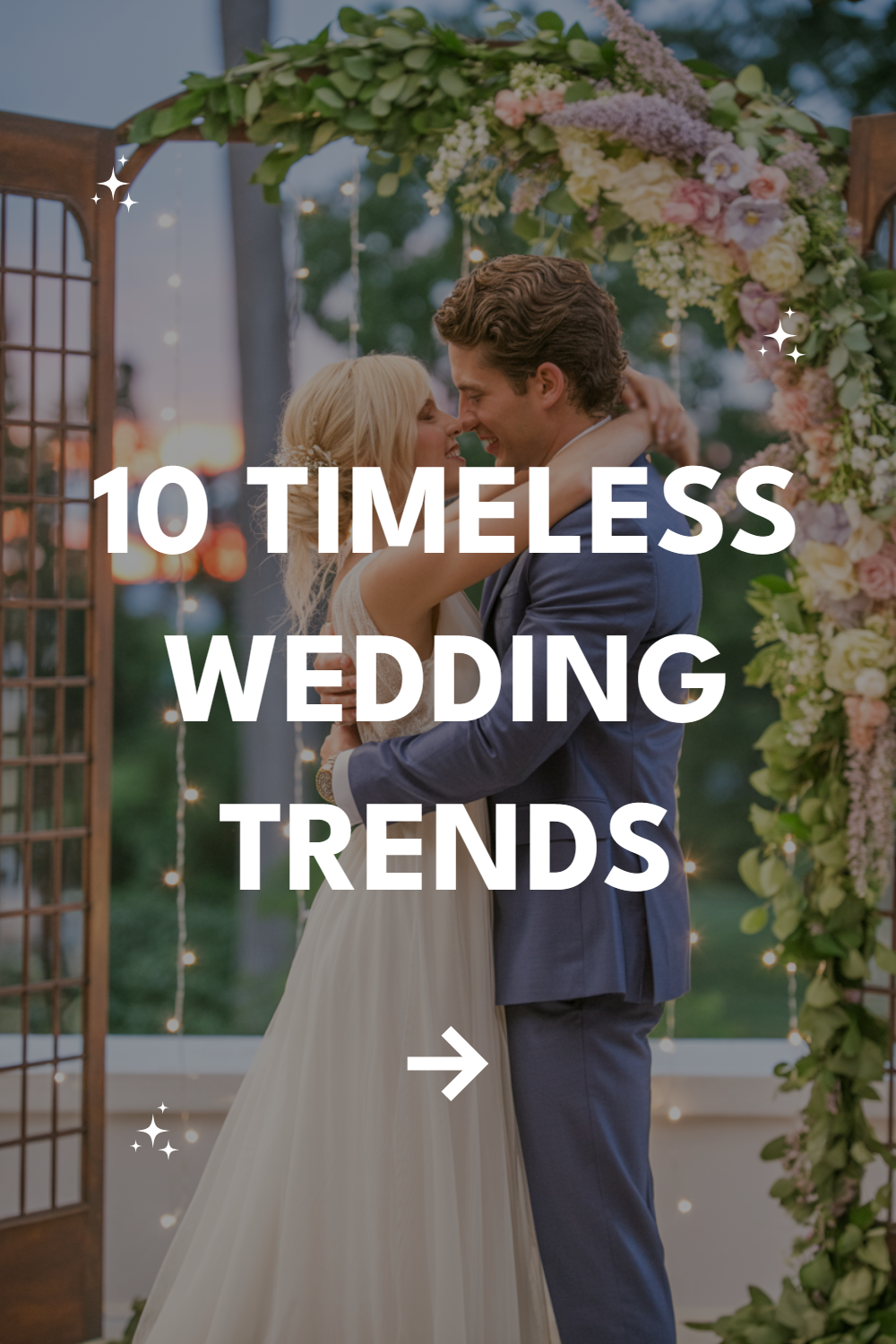 Couple under floral arch celebrating wedding, showcasing timeless trends and romantic ambiance.
