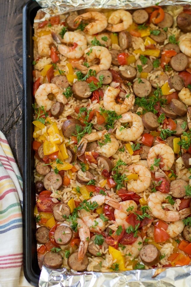Jambalay with onion, bell peppers, and sausage served on a sheet pan.