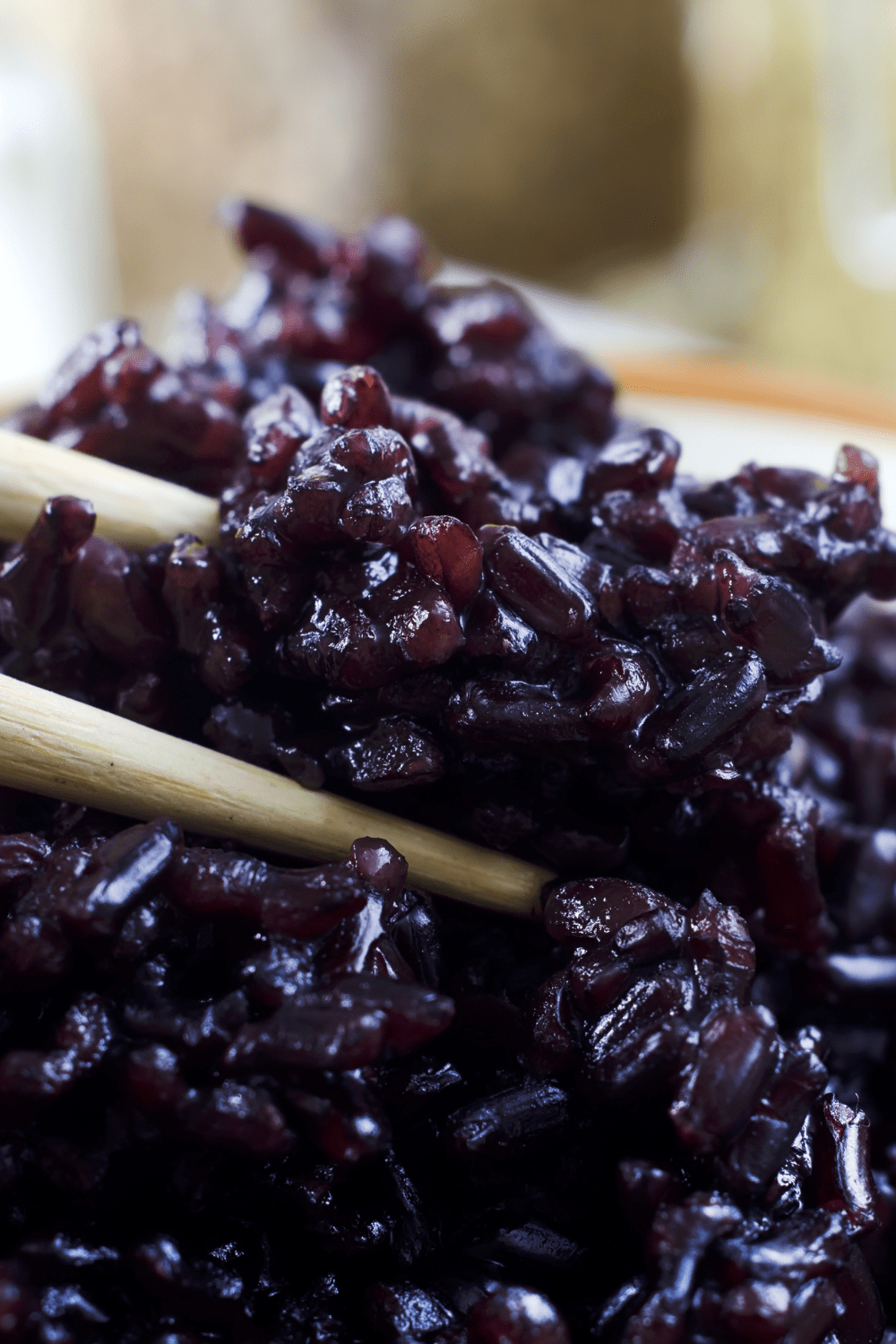 Black rice on a plate scooped with a wooden chopsticks.