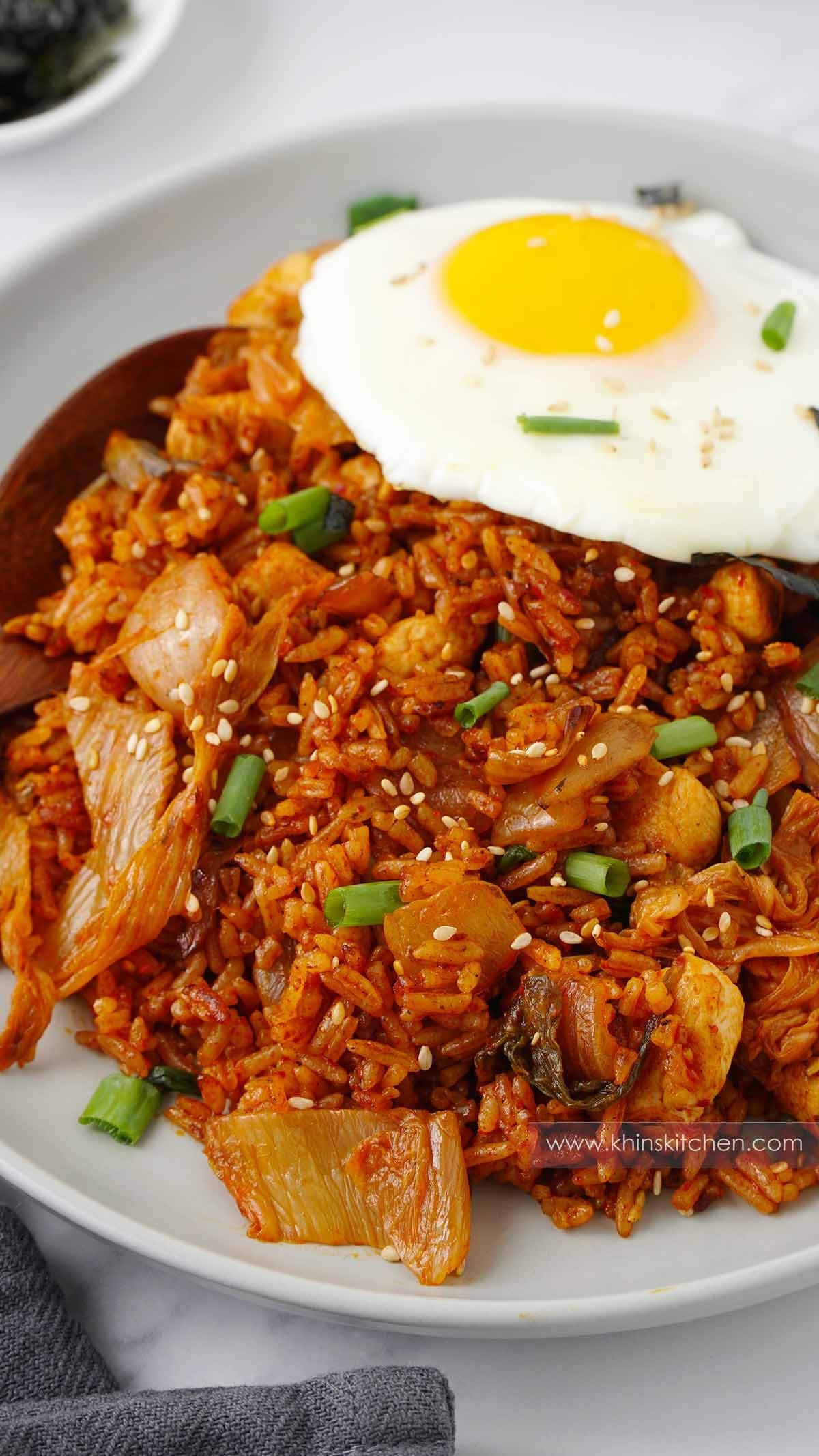 Korean kimchi fried rice topped with a sunny side egg in a white plate.