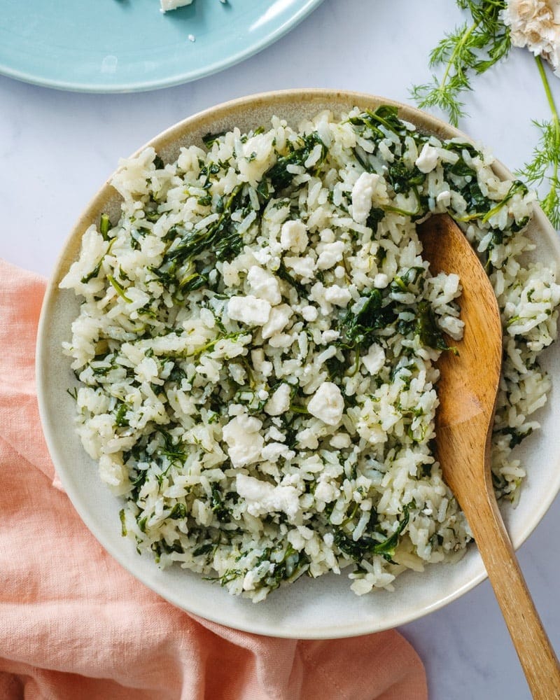 Rice in a plate mixed with spinach and feta cheese.