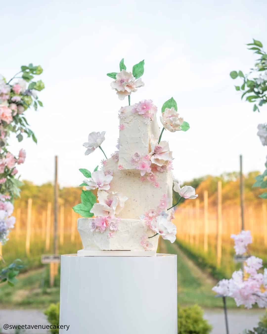 unique wedding cakes three tier square textured cake with pink flowers outdoors sweetavenuecakery