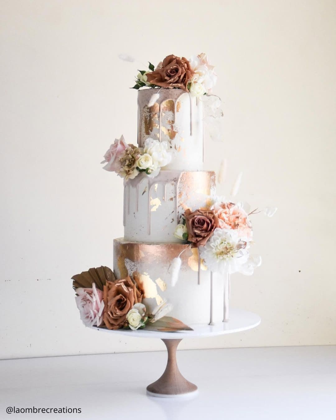 unique wedding cakes three tiered white and gold drip cake with earthy toned roses laombrecreations