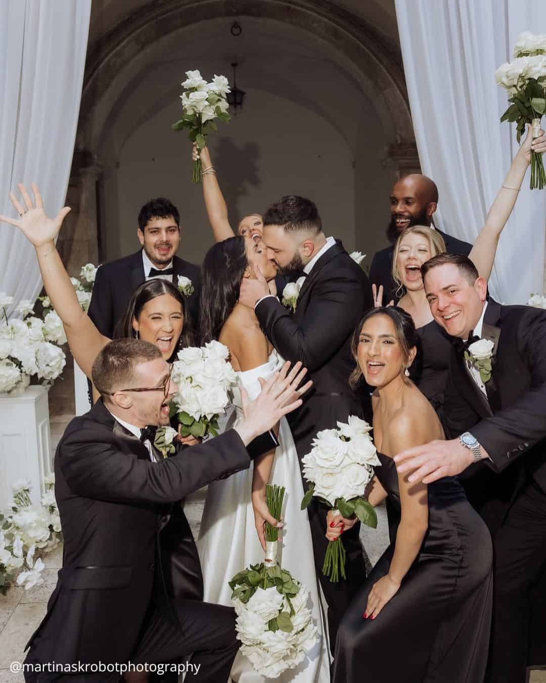 wedding photos brides kissing with fun friends all with a bouquet in hands in black and white colors martinaskrobotphotography